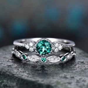 Macro shot of emerald halo ring set with vintage micro-pave diamonds on dark rock