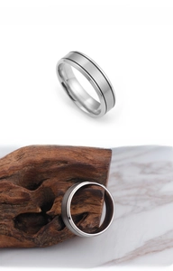 Detail of silver stainless steel ring featuring brushed texture and parallel black lines