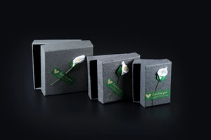 Three grey jewelry boxes with calla lily and green labels on black background
