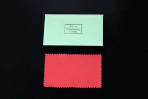 Close-up of red silver polishing cloth with light green envelope packaging on black background