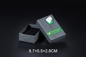 Detail of dark gray marble texture jewelry gift box with white calla lily and sticker
