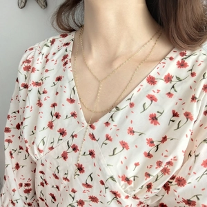 Detail view of a 925 sterling silver gold layered Y-necklace on a floral dress