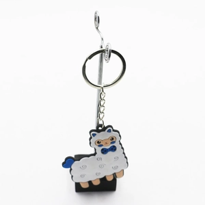 Cartoon white alpaca PVC keychain with blue bow and silver metal ring on white background