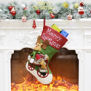 Festive green Christmas stocking with reindeer plush hanging on white fireplace