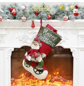 Close-up of a snowman Christmas stocking hanging by a fireplace with festive decor