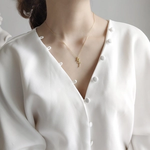 Detailed view of rose flower pendant necklace in gold worn by a model in casual attire