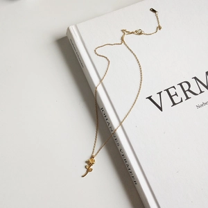 Macro shot of rose gold rose pendant necklace resting on a white vintage art book