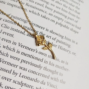 Detail of rose gold flower pendant with leaf textures on a vintage book page background