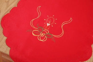 Detail of red Christmas table runner with golden embroidery of candles and holly leaves