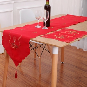 Detailed embroidery and festive red tassels on a Christmas table runner and placemat set