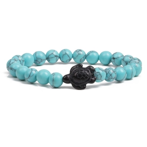 Detail of beaded turquoise bracelet featuring a black carved sea turtle charm centerpiece