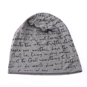 Detail of grey knitted beanie featuring all-over black handwritten script pattern