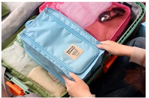 Waterproof light blue travel shoe bag with zipper and handle inside a suitcase