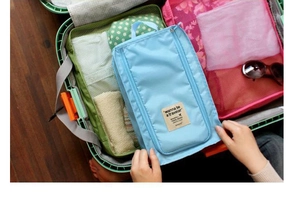 Close-up of light blue waterproof travel shoe bag with handle inside a green suitcase