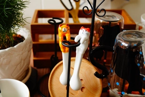 Detail of cute hand-painted ceramic cat spoons hanging on a rack for home kitchen decor
