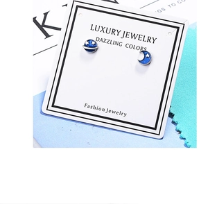 Macro shot of blue planet and moon enamel stud earrings on a luxury jewelry card
