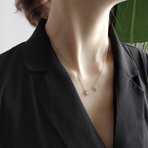 Close-up of gold safety pin necklace with pavé zircon detail on a female model