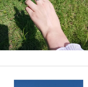 Close-up of minimalist silver star ring worn on finger against a green grass background