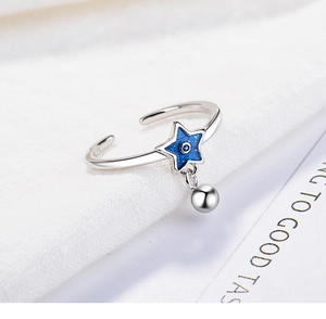 Detail of S925 sterling silver ring with blue star charm and dangling bead on fabric