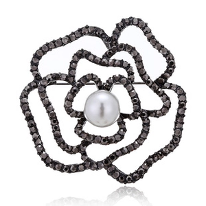 Close-up of black camellia flower brooch with rhinestones and a central white pearl