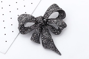 Detail shot of a black bow brooch featuring vintage crystals on a metal base