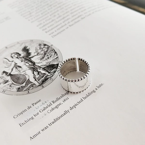 Close-up of S925 sterling silver wide ring with beaded edges on a vintage book page