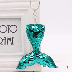 Green sequined mermaid tail keychain with silver metal ring on a minimalist background