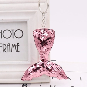 Pink sequin mermaid tail keychain with silver metal ring on a white decorative frame