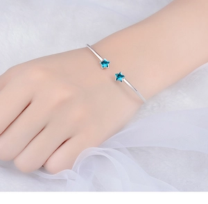Close-up of adjustable silver star bangle with two vibrant blue star crystals on wrist