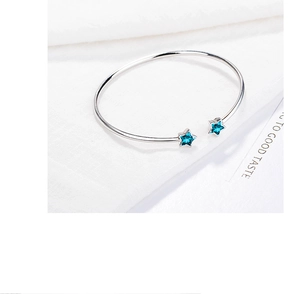 Detailed shot of open silver bracelet featuring two sky blue star-shaped crystals