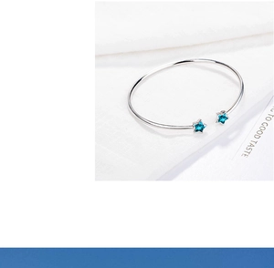 Macro detail of silver open bangle with blue star-shaped gemstones on white background