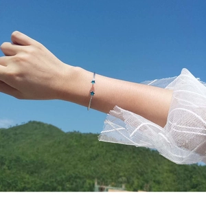Outdoor lifestyle shot of a silver star open bracelet with blue star charms on wrist