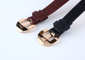 Detail of dark brown and black PU leather belts with polished gold crescent metal buckles