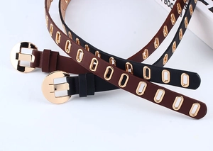 Detailed view of black and brown PU leather belts with metal eyelets and gold buckles