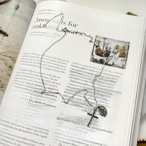 Close-up of vintage silver cross and virgin mary medal pendants on open book