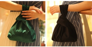 Wristlet velvet pouch handbags in dark green and black shown in a lifestyle indoor setting