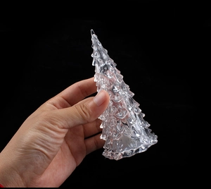 Close-up of a hand holding a transparent crystal Christmas tree night light with high clarity