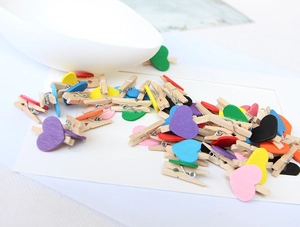 Close-up of colorful heart-shaped wooden clips on a white envelope for photo display