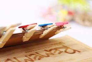 Close-up of mini wooden photo clips with colorful heart shapes on a decorative base