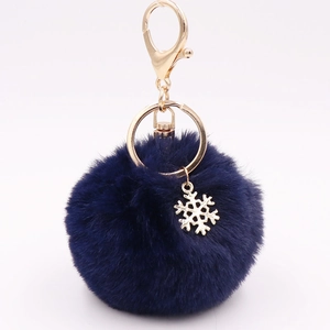 Detail shot of navy blue faux fur pompom with golden snowflake pendant and keyring
