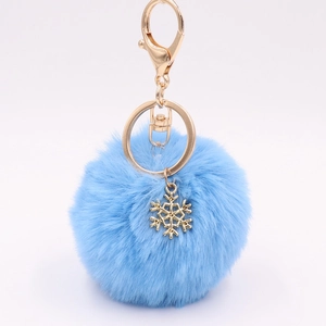Light blue fluffy faux fur pompom keychain with golden alloy snowflake charm on white background