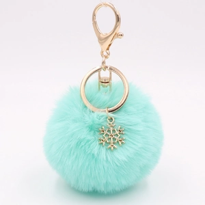 Detailed view of plush mint green pompom keychain with golden snowflake charm and clasp