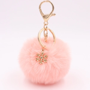 Detailed view of pink plush ball keychain with golden snowflake charm and metal ring