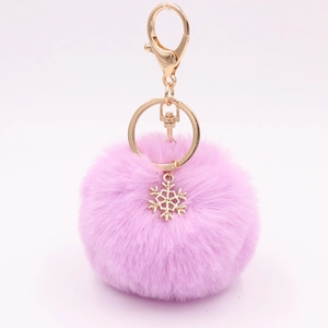 Close-up of pink fluffy faux fur pompom keychain with golden snowflake charm and clasp