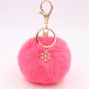 Detailed close-up of a fluffy bright pink pompom keychain with a gold snowflake charm