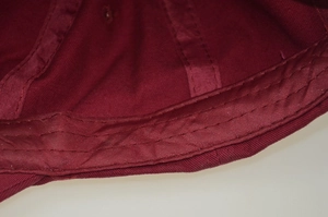 Detailed macro view of the inner stitching and sweatband of the red cotton baseball cap