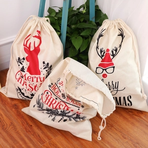 Large drawstring Christmas gift bags made of linen with festive prints on wooden floor