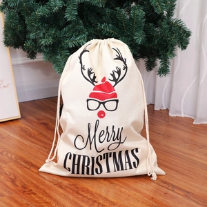 Large linen drawstring Christmas gift bag with Santa hat and reindeer print on wooden floor
