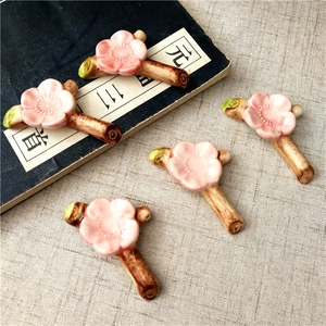 Detail of pink plum blossom ceramic chopstick rests on rustic branch base over vintage book