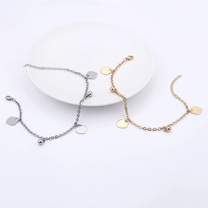 Elegant gold and silver heart charm anklets displayed on a white ceramic plate for women